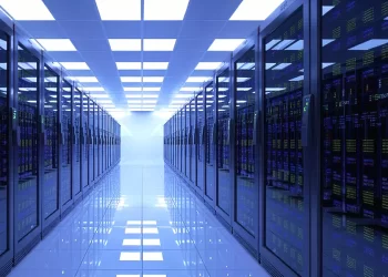 Data center corridor with tall server racks on both sides under bright blue-tinted lighting, reflecting off a glossy floor.