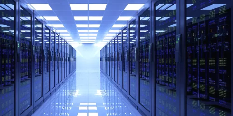 Data center corridor with tall server racks on both sides under bright blue-tinted lighting, reflecting off a glossy floor.