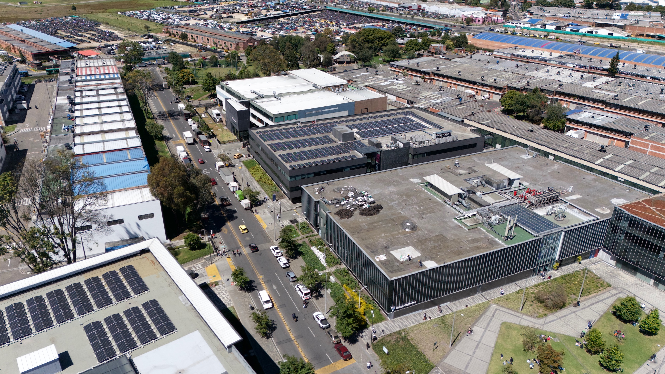 Aerial view of a modern office campus with solar panels on rooftops, parking lots, and green spaces nearby