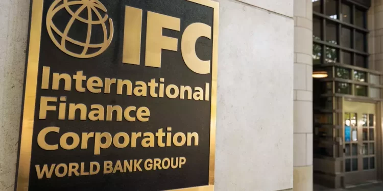 Gold-framed sign on a stone wall reading 'IFC International Finance Corporation World Bank Group' with a globe logo, outside a office building.