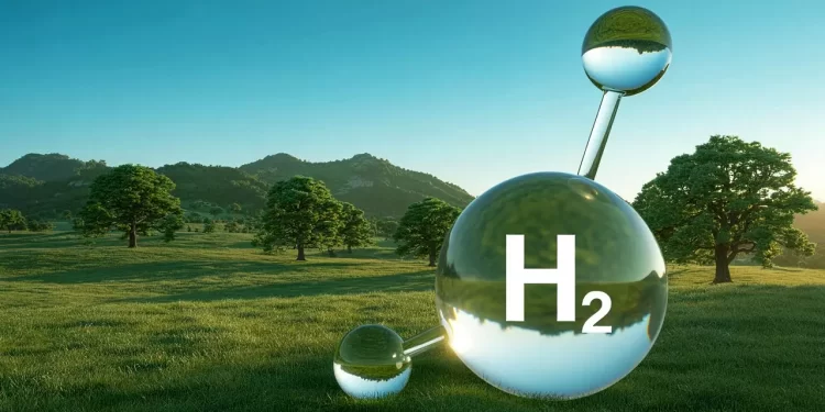 Large glass H2 molecule model on a sunny grassy field with trees and hills in the background, the big sphere labeled H2.