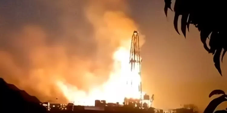 Rocket on a launchpad blasting flames into the night sky with a large plume of fire and smoke.
